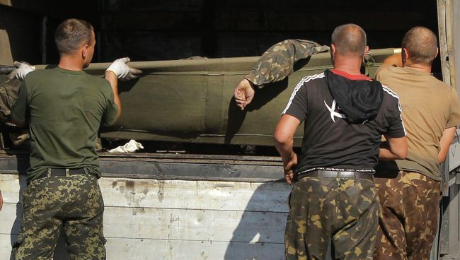 Украинские военные грузят в грузовик тела погибших товарищей Украинские военные грузят в грузовик тела погибших товарищей