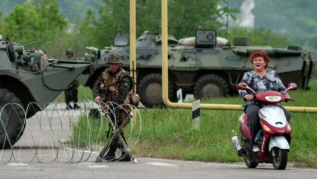 Женщина на скутере проезжает КПП украинской армии по дороге в деревню Спиваковка Луганской области. Архивное фото