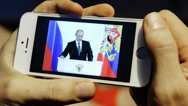 Житель Новосибирска смотрит на экране смартфона телевизионную трансляцию послания президента РФ Владимира Путина к Федеральному Собранию Житель Новосибирска смотрит на экране смартфона телевизионную трансляцию послания президента РФ Владимира Путина к Федеральному Собранию