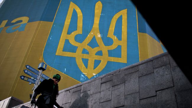 Женщина проходит мимо огромного украинского флага в центре Киева, архивное фото Женщина проходит мимо огромного украинского флага в центре Киева, архивное фото