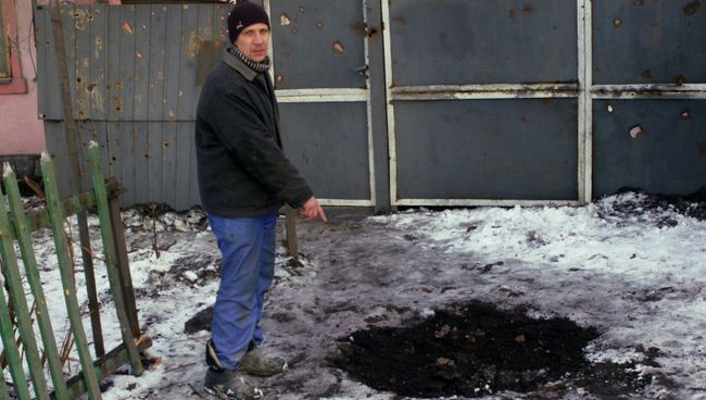 Житель Донецка показывает воронку от снаряда у дома в Червоногвардейском районе Житель Донецка показывает воронку от снаряда у дома в Червоногвардейском районе