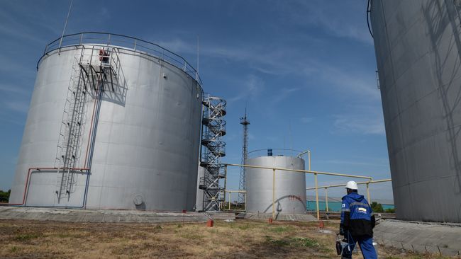 Сотрудник нефтебазы возле резервуаров для хранения топлива