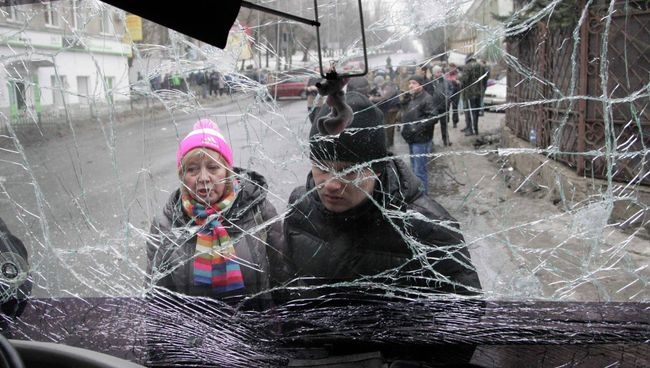 Люди смотрят через лобовое стекло обстрелянного троллейбуса в Донецке Люди смотрят через лобовое стекло обстрелянного троллейбуса в Донецке