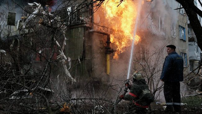 Пожарный тушит пожар в жилом доме, возникший в результате обстрела Донецка украинскими силовиками Пожарный тушит пожар в жилом доме, возникший в результате обстрела Донецка украинскими силовиками