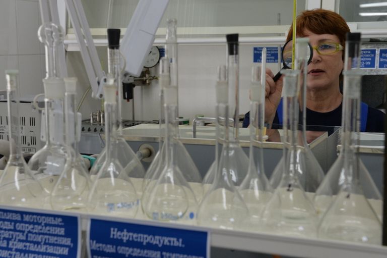 Сотрудница испытательной лаборатории нефтепродуктов во время работы с пробой топлива