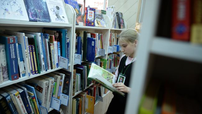 Девочка читает книгу в библиотеке. Архивное фото