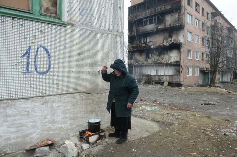 Жительница города Дебальцево готовит еду на костре на улице у жилого многоквартирного дома, пострадавшего в результате обстрелов во время боевых действий Жительница города Дебальцево готовит еду на костре на улице у жилого многоквартирного дома, пострадавшего в результате обстрелов во время боевых действий