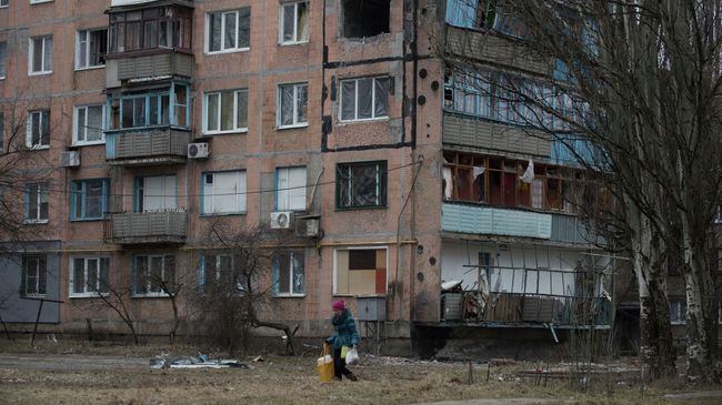 Женщина проходит мимо разрушенного жилого дома в Авдеевке. Архивное фото Женщина проходит мимо разрушенного жилого дома в Авдеевке. Архивное фото