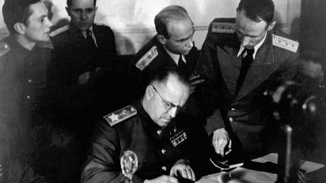 Маршал Советского Союза Георгий Константинович Жуков (в центре) подписывает Акт о безоговорочной капитуляции фашистской Германии в Карлсхорсте в Берлине