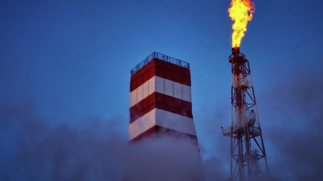 Вид на буровую вышку и газовый факел морской нефтеперерабатывающей платформы