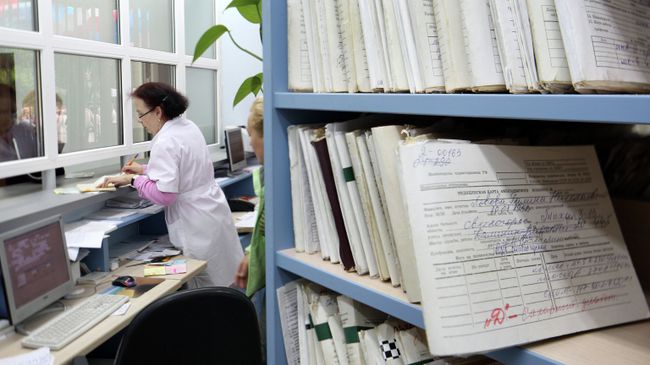Медицинский работник выдает медицинскую карту пациенту в регистратуре поликлиники Медицинский работник выдает медицинскую карту пациенту в регистратуре поликлиники