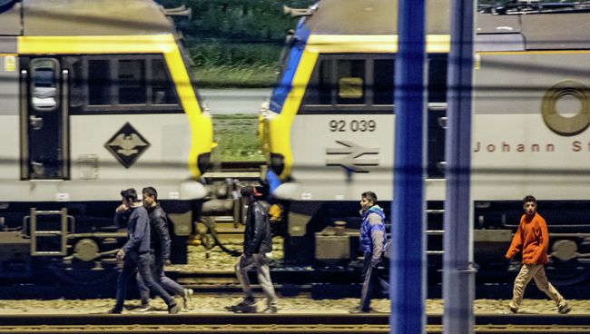 Мигранты идут вдоль железнодорожных путей в терминале Евротуннеля. Архивное фото Мигранты идут вдоль железнодорожных путей в терминале Евротуннеля. Архивное фото