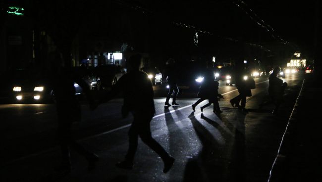 Жители Симферополя переходят автодорогу в свете фар автомобилей Жители Симферополя переходят автодорогу в свете фар автомобилей