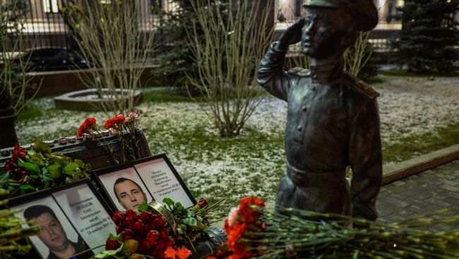 Портреты погибших в Сирии подполковника Олега Пешкова и матроса Александра Позынича и цветы у памятника героям фильма Офицеры перед зданием Министерства обороны РФ в Москве. Архивное фото