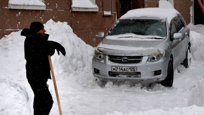 Мужчина убирает снег во Владивостоке. Архивное фото Мужчина убирает снег во Владивостоке. Архивное фото