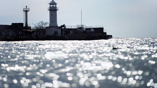 Маяк городского порта Ялты в акватории Черного моря. Архивное фото Маяк городского порта Ялты в акватории Черного моря. Архивное фото