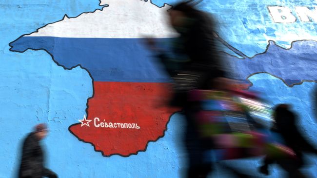Прохожие у нарисованной на стене карты Крыма в цветах российского флага в Москве. Архивное фото