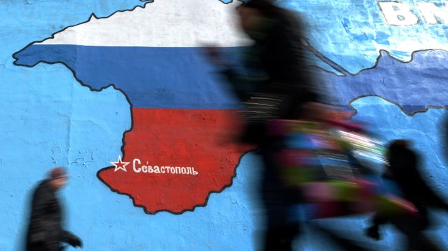 Прохожие у нарисованной на стене карты Крыма в цветах российского флага в Москве. Архивное фото Прохожие у нарисованной на стене карты Крыма в цветах российского флага в Москве. Архивное фото