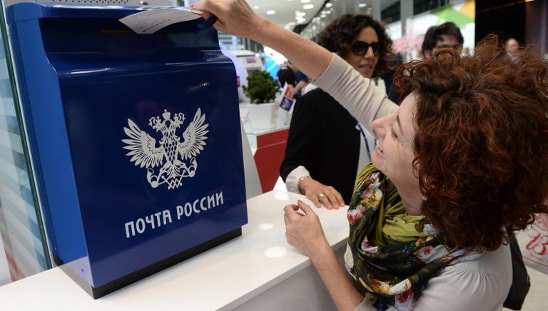 Посетительница XX Петербургского международного экономического форума опускает открытку в ящик Почты России
