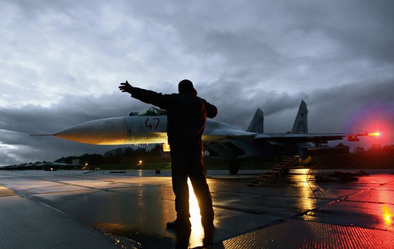 Военный техник дает отмашку на взлет истребителя Су-27