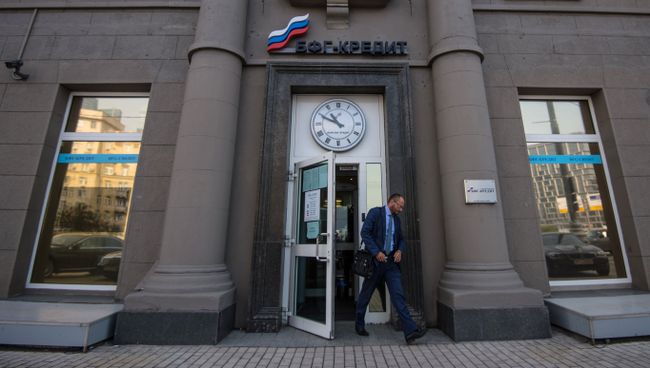 Мужчина у входа в офис банка БФГ-Кредит на Кутузовском проспекте в Москве. 27 июля Центральный банк России (ЦБ РФ) отозвал лицензию на осуществление банковских операций у банка БФГ-Кредит