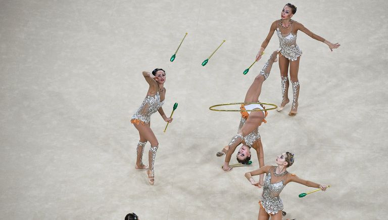 Спортсменки сборной России выступают в упражнении с шестью булавами и двумя обручами в финале групповых соревнований по художественной гимнастике