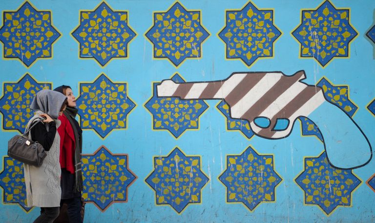 Женщины идут вдоль стены здания бывшего посольства США в Тегеране Женщины идут вдоль стены здания бывшего посольства США в Тегеране