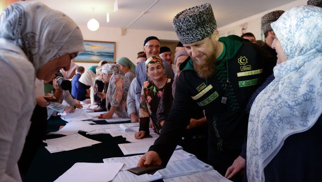 Временно исполняющий обязанности главы Чечни Рамзан Кадыров (второй справа) в единый день голосования на избирательном участке №165 в селе Центарой