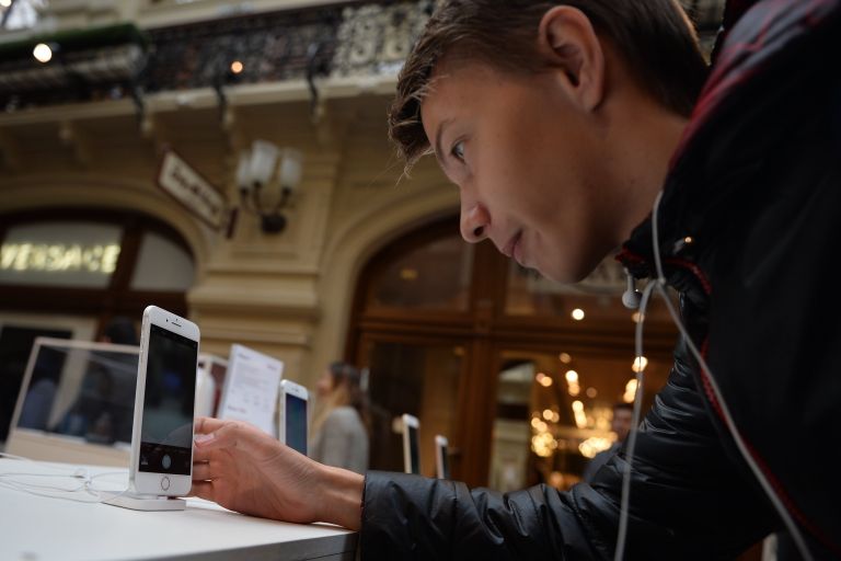 Молодой человек рассматривает новые смартфоны iPhone 7 и iPhone 7 Plus в торговом центре ГУМ Молодой человек рассматривает новые смартфоны iPhone 7 и iPhone 7 Plus в торговом центре ГУМ