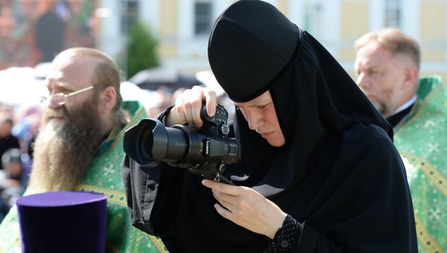 Монахиня с фотокамерой во время литургии Монахиня с фотокамерой во время литургии