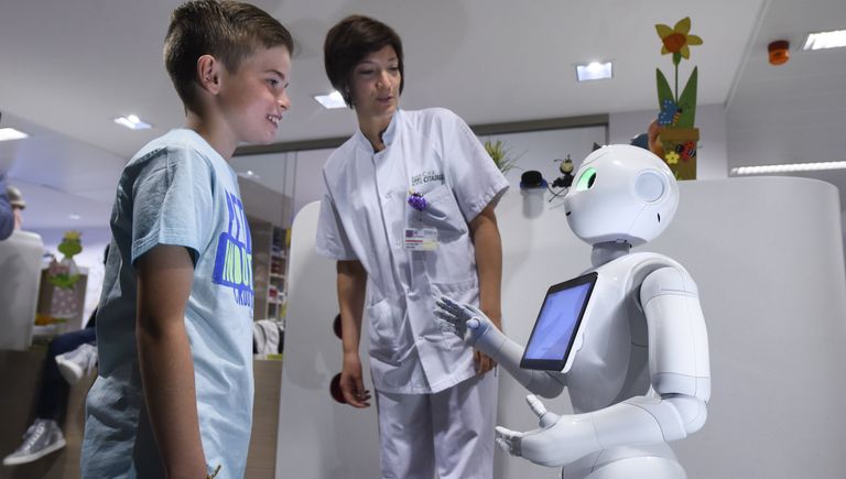 Мальчик разговаривает с роботом Pepper в городе Льеж в Бельгии Мальчик разговаривает с роботом Pepper в городе Льеж в Бельгии