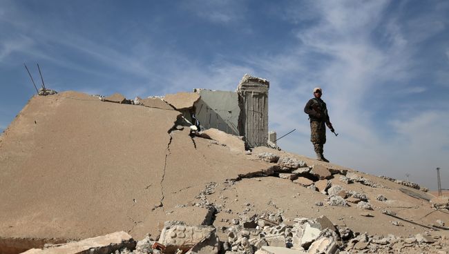 Боец Демократических сил Сирии у разрушенного здания в Ракке. 7 ноября 2016 года Боец Демократических сил Сирии у разрушенного здания в Ракке. 7 ноября 2016 года