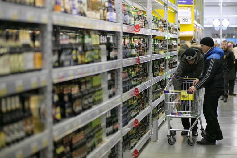 Покупатели выбирают пиво в отделе алкоголя Покупатели выбирают пиво в отделе алкоголя