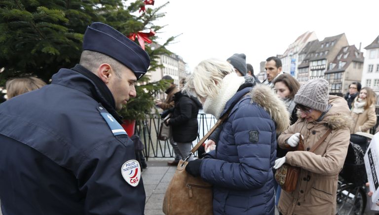 Сотрудник полиции проверяет сумки у посетителей рождественского базара в Страсбурге, Франция Сотрудник полиции проверяет сумки у посетителей рождественского базара в Страсбурге, Франция