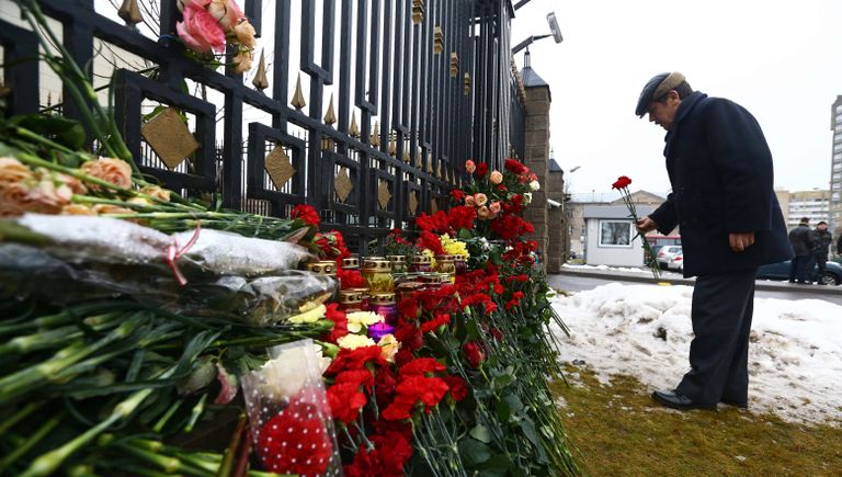 Мужчина возлагает цветы в память о погибших в авиакатастрофе Ту-154 в Сочи у посольства России в Минске