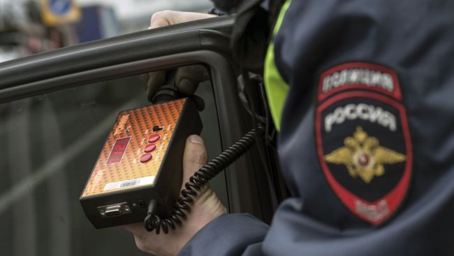 Сотрудник ГИБДД проверяет с помощью прибора тонировку стекла автомобиля. Архивное фото Сотрудник ГИБДД проверяет с помощью прибора тонировку стекла автомобиля. Архивное фото