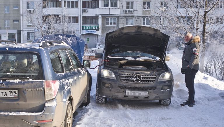 Автомобилист заряжает аккумулятор своего автомобиля в Москве Автомобилист заряжает аккумулятор своего автомобиля в Москве
