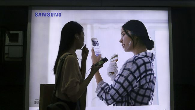 Девушка на фоне рекламы смартфона Galaxy Note 7 компании Samsung. Архивное фото Девушка на фоне рекламы смартфона Galaxy Note 7 компании Samsung. Архивное фото