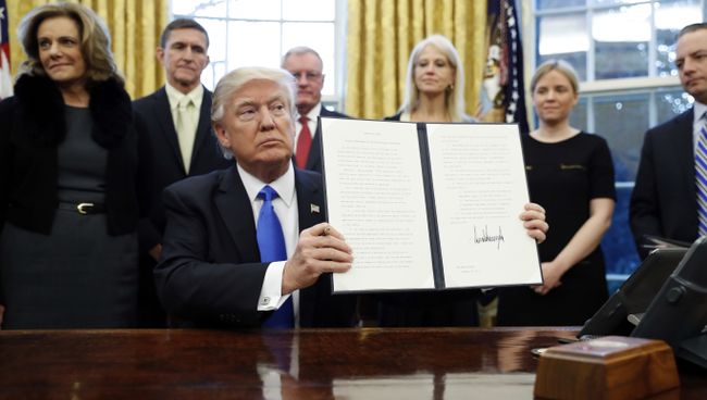Президент США Дональд Трамп держит один из только что подписанных указов. 28 января 2017 Президент США Дональд Трамп держит один из только что подписанных указов. 28 января 2017