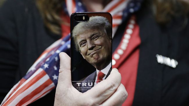 Женщина держит телефон с фотографией Дональда Трампа во время предвыборной кампании в США Женщина держит телефон с фотографией Дональда Трампа во время предвыборной кампании в США