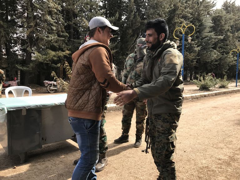 Боец сирийской армии жмет руку боевику из вооруженной оппозиции после досмотра на КПП города Сергая
