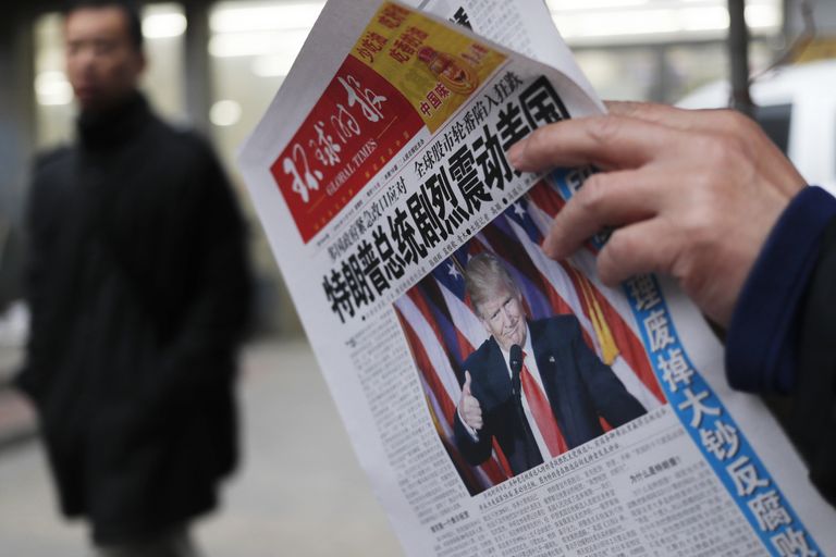 Мужчина читает газету с новостью об избрании Дональда Трампа президентом США. Пекин, 10 ноября 2016 года 