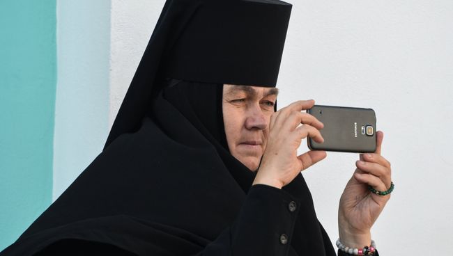 Монахиня фотографирует на мобильный телефон богослужение в Троице-Сергиевой лавре Монахиня фотографирует на мобильный телефон богослужение в Троице-Сергиевой лавре