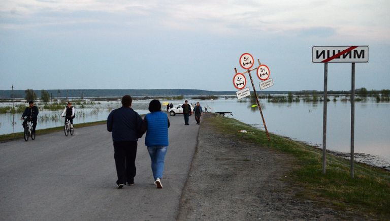 Местные жители на дороге в городе Ишим Тюменской области, подтопленной в результате сильного поднятия воды в реках Ишим и Карасуль Местные жители на дороге в городе Ишим Тюменской области, подтопленной в результате сильного поднятия воды в реках Ишим и Карасуль