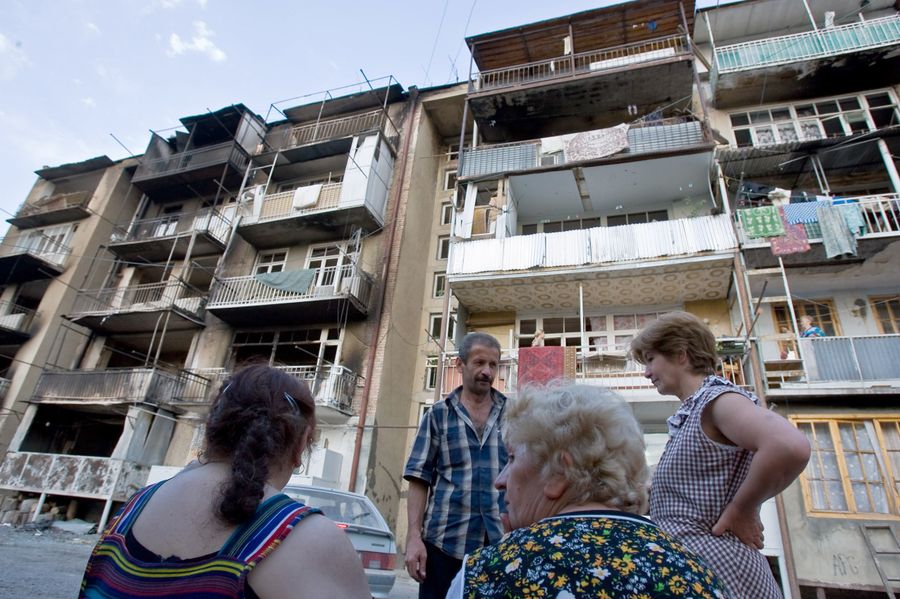 Жители Цхинвали возле своего дома, пострадавшего от пуль и снарядов в ходе обстрелов. 14 августа 2008 года