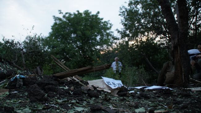 Местный житель стоит у воронки от снаряда во дворе соседского дома. Архивное фото Местный житель стоит у воронки от снаряда во дворе соседского дома. Архивное фото