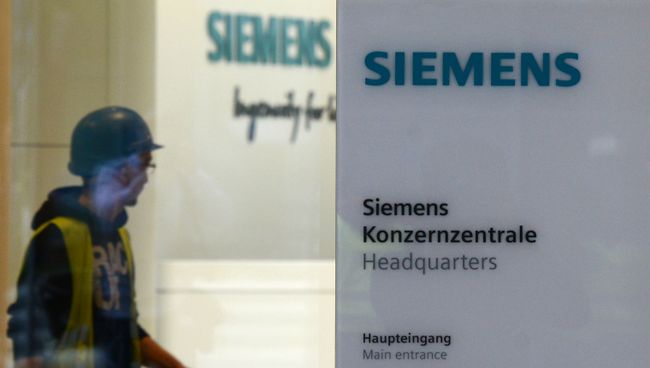 Рабочий у входа в штаб-квартиру компании Siemens в Мюнхене, Германия