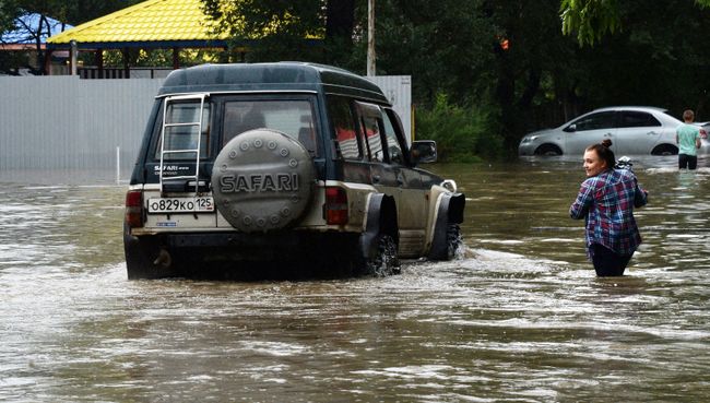 Женщина у автомобиля на затопленной улице Уссурийска. 7 августа 2017 Женщина у автомобиля на затопленной улице Уссурийска. 7 августа 2017