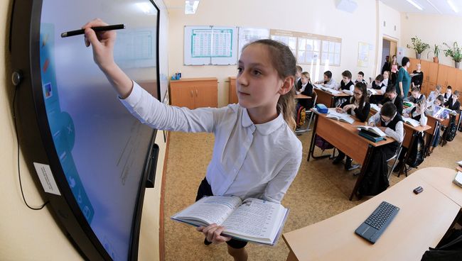 Ученица выполняет задание возле интерактивной доски во время урока в московской школе. Архивное фото Ученица выполняет задание возле интерактивной доски во время урока в московской школе. Архивное фото
