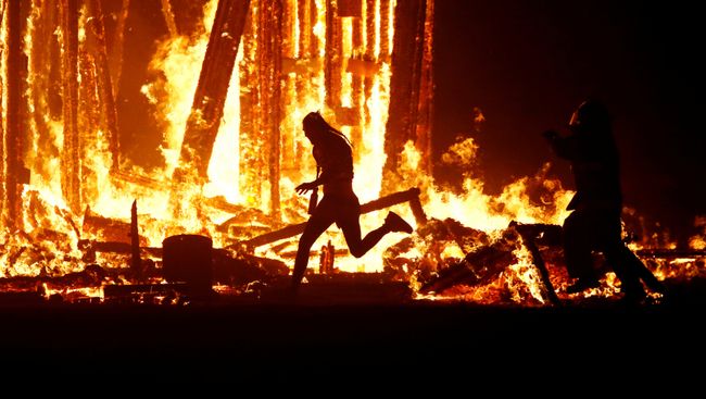 Мужчина пытается пробежать сквозь пламя, игнорируя пожарных, на фестивале Burning Man в пустыне Невада, США. 2 сентября 2017 Мужчина пытается пробежать сквозь пламя, игнорируя пожарных, на фестивале Burning Man в пустыне Невада, США. 2 сентября 2017